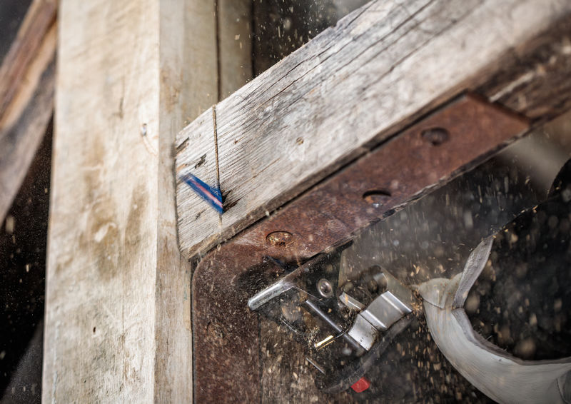 Eine Person mit Schutzausrüstung durchtrennt mit einer Stichsäge einen Holzbalken. Anwendungsbild